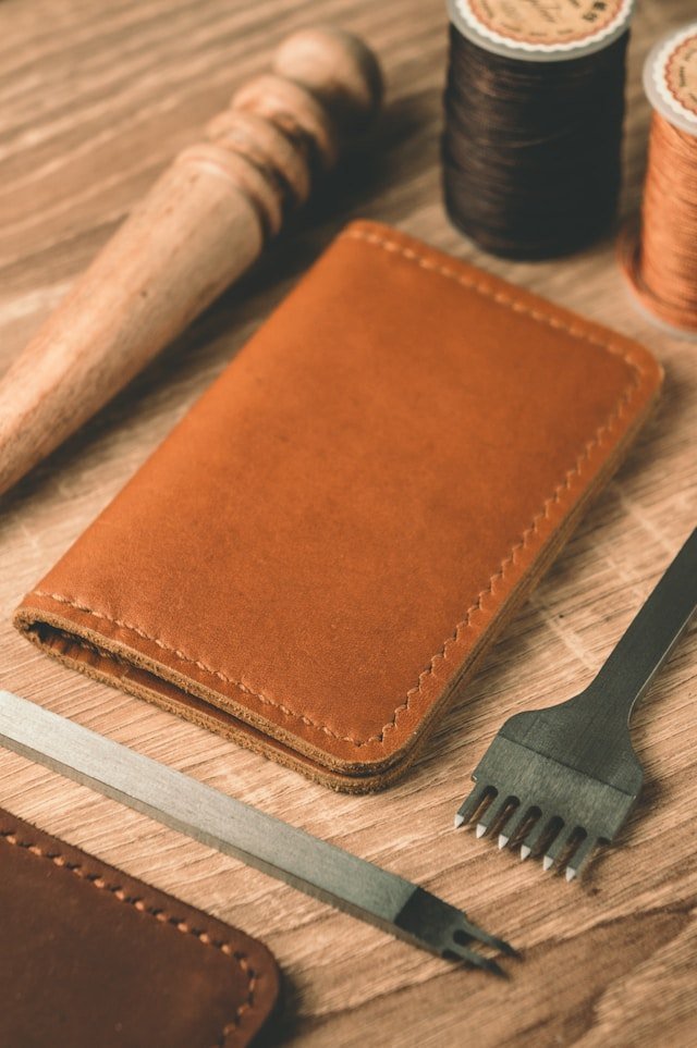 Leather wallet and handcrafting tools on a wooden workbench